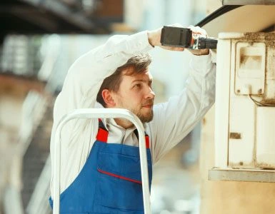 Installer drilling outdoor CCTV camera as part of commercial surveillance setup in Qatar.