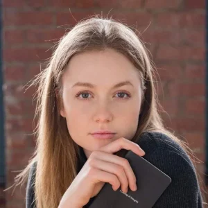Serious woman with blonde hair holding notebook.
