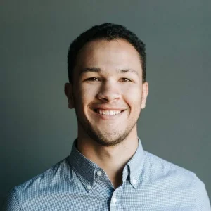 Smiling young man with curly hair in checkered shirt.