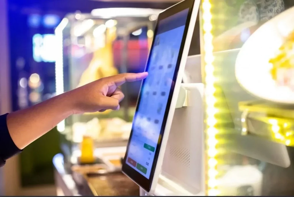 Close-up of a customer using a touchscreen token dispenser for automated queue allocation.