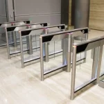 Speed gate turnstiles with glass panels installed in office entry to enable secure, one-at-a-time access.