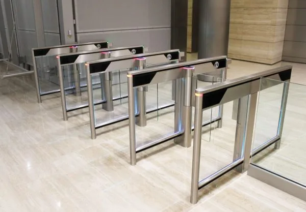 Speed gate turnstiles with glass panels installed in office entry to enable secure, one-at-a-time access.