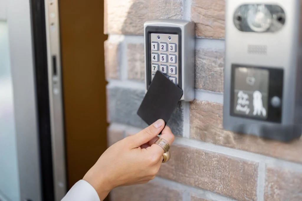 Person using a key card on a wall-mounted keypad access control system.
