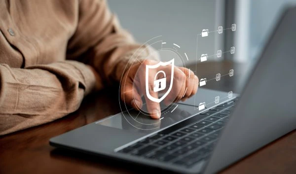 Person using laptop with digital shield and padlock overlay.